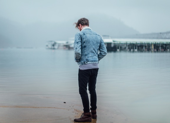 Premium Photo | Fashion model young man in stylish denim jacket in ripped  fashionable blue jeans in trendy white sneakers sit on sidewalk near road  in city. handsome guy in vintage casual